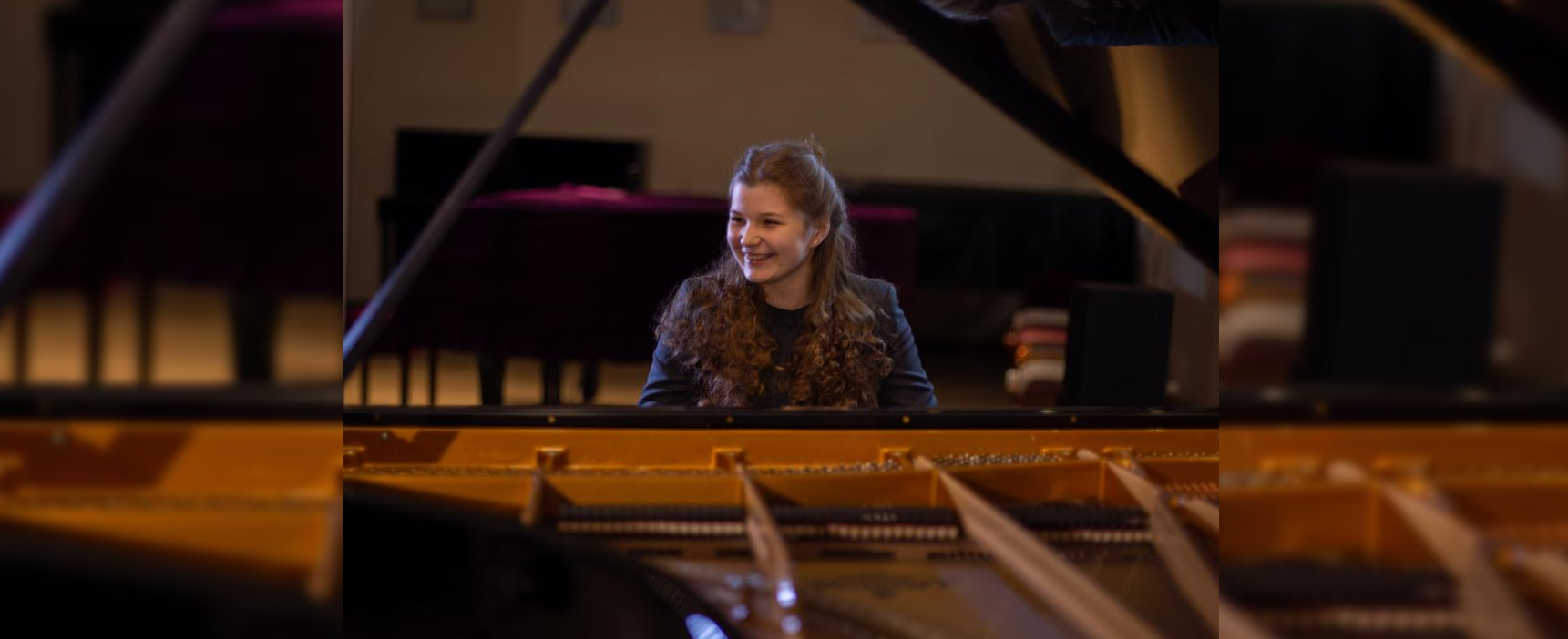 Khrystyna Mykhailichenko smiling whilst sitting at the piano
